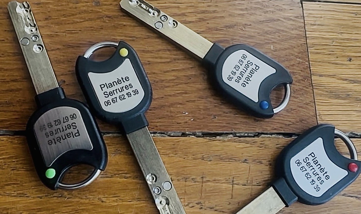 Jeu de clés protégées RB-LOCKS à tête plastique gravée « Planète Serrures · 06 67 62 19 39 », équipées de pastilles de couleur permettant d'identifier chaque porte d'un coup d'œil
